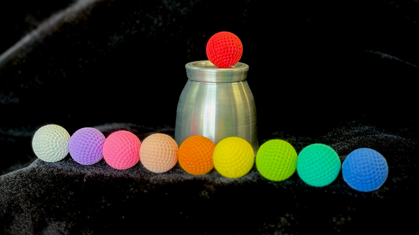 Colorful balls arranged in a line with a metallic container on a dark background